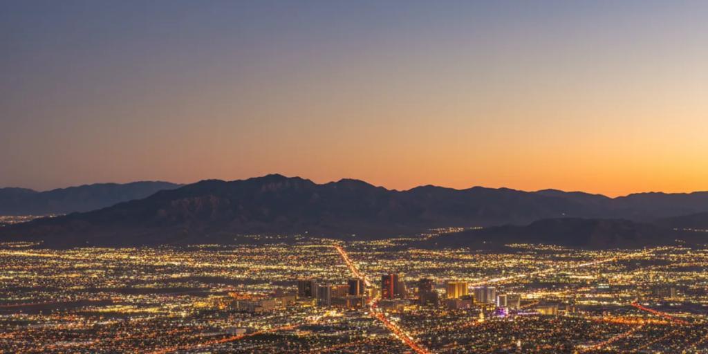 Das leuchtende Wüstental von Las Vegas in der Abenddämmerung, die Neontürme des Strip erheben sich aus der Mojave