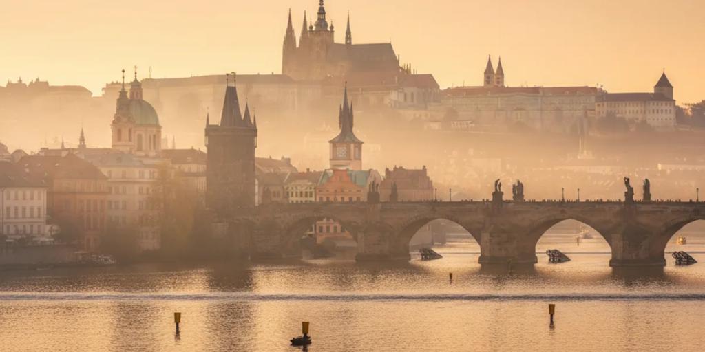 Die Statuen der Karlsbrücke und die Prager Burg, die durch den Morgennebel aufragt