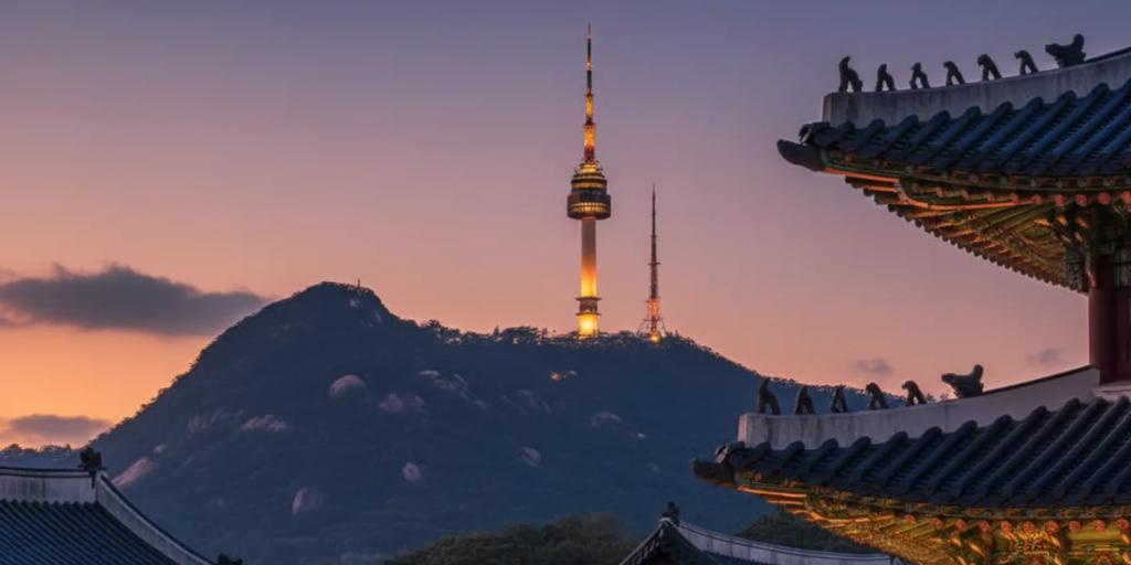 Die Dachlinien des Gyeongbokgung-Palasts im Vordergrund, dahinter erhebt sich der N Seoul Tower auf dem Namsan
