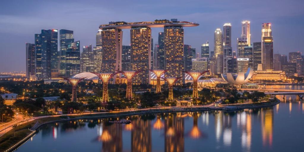 Die Skyline von Marina Bay und die Supertrees von Gardens by the Bay, die zur blauen Stunde leuchten
