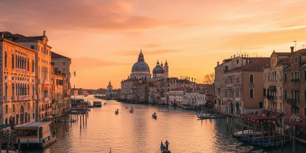 Gondeln, die in der Abenddämmerung am Canal Grande vertäut sind, mit den Kuppeln der Salute dahinter